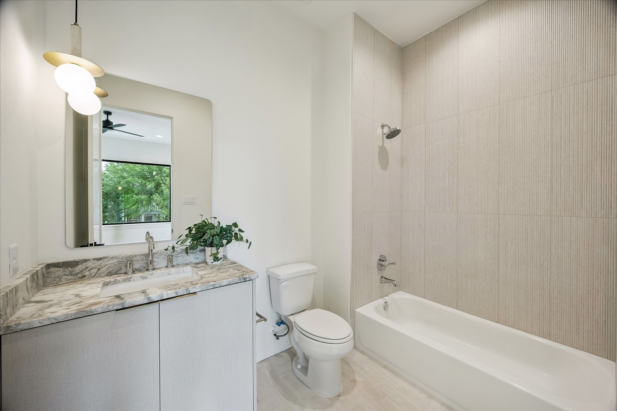 122 East 4th Street Houston, TX 77007 - Photo 28 of 38 En-suite bath – features a shower/tub combo, designer pendant lighting, and Taj Mahal quartz countertop.
