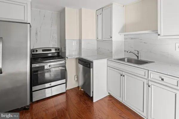 a kitchen with granite countertop white cabinets and stainless steel appliances