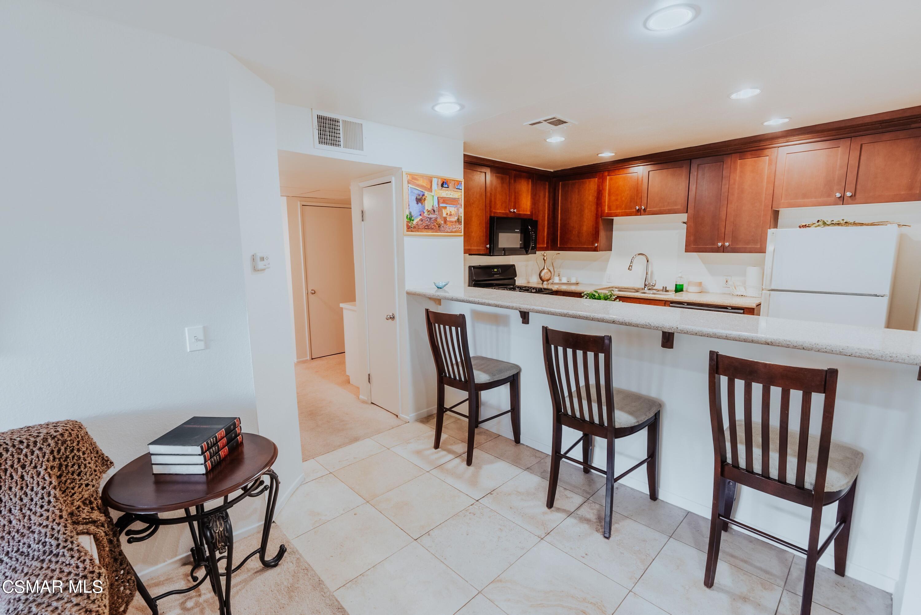 20253 Keswick Street, Unit 233 Winnetka, CA 91306 - Photo 5 of 18 a kitchen with a dining table chairs and white cabinets