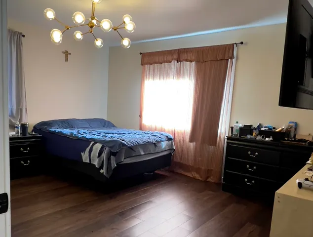 a bedroom with a bed and a flat tv screen on dresser