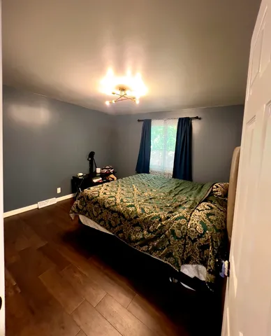 a bed sitting in a bedroom next to a lamp with lamp on desk