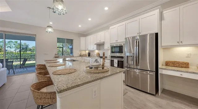 a kitchen with granite countertop a refrigerator a stove a sink a dining table and chairs