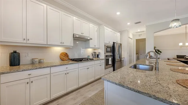 a kitchen with granite countertop a sink stainless steel appliances and white cabinets