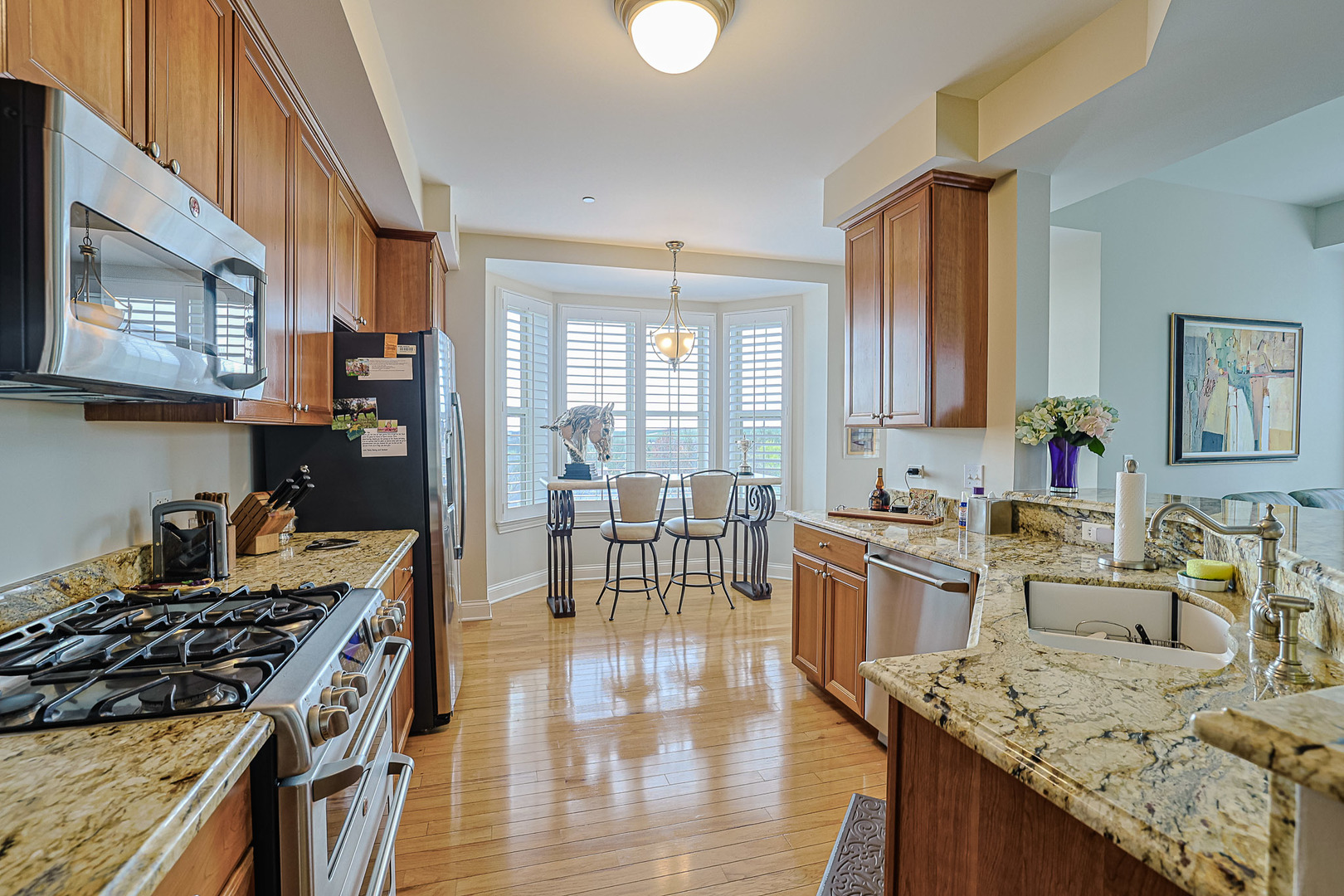 2700 Summit Drive, Unit 401 Glenview, IL 60025 - Photo 13 of 31 a kitchen with stainless steel appliances granite countertop a stove top oven a sink dishwasher a dining table and chairs with wooden floor