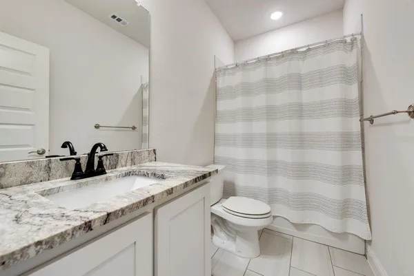 a bathroom with a granite countertop sink toilet and shower