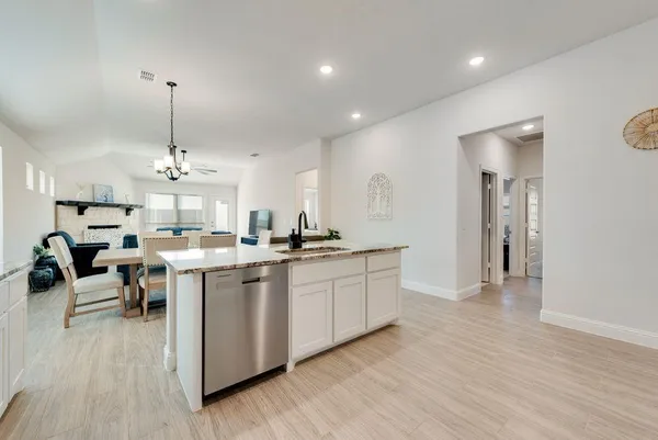 a open kitchen with stainless steel appliances granite countertop a sink dishwasher a stove with wooden floor