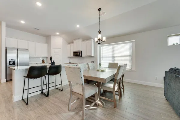 a view of a dining room with furniture a kitchen and chandelier