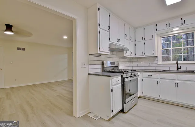 a kitchen with cabinets appliances a sink and a window