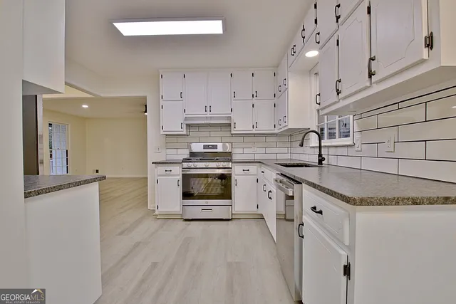a kitchen with granite countertop white cabinets and white appliances