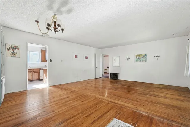 a view of an empty room with wooden floor and a chandelier