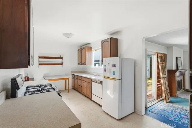 a kitchen with stainless steel appliances a stove a sink refrigerator and a fireplace