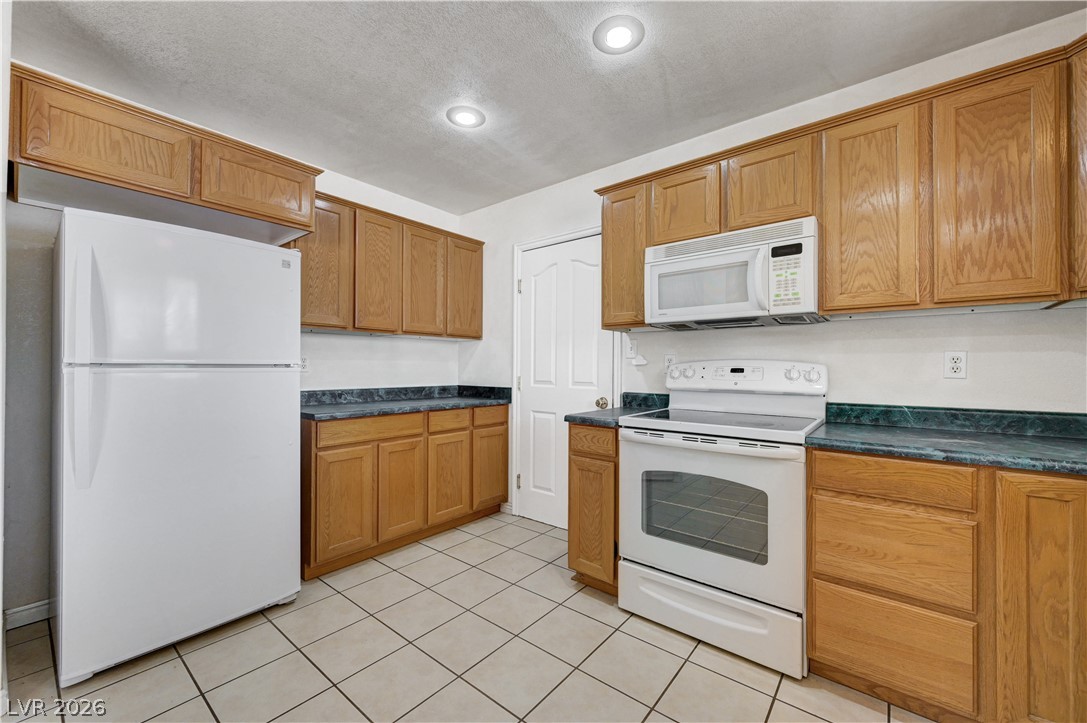 1272 Liston Avenue Logandale, NV 89021 - Photo 21 of 61 A well-lit kitchen with natural wood cabinetry and resilient tile flooring.