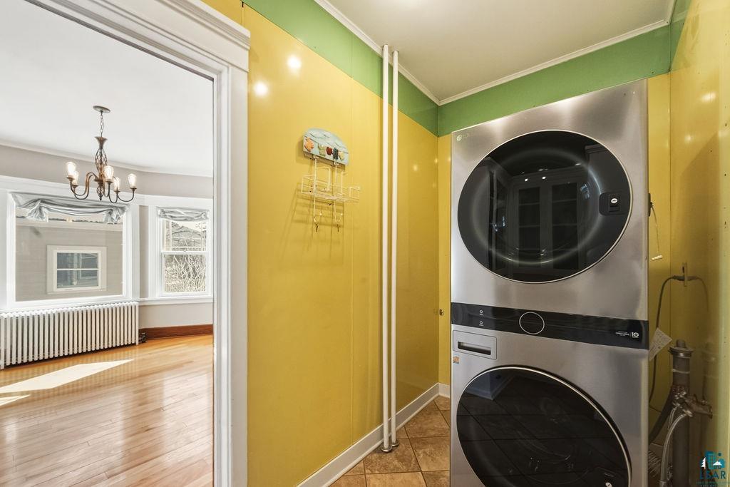 4220 McCulloch Street Duluth, MN 55804 - Photo 19 of 27 Laundry area featuring crown molding, radiator heating unit, suspended lighting, stacked washer / dryer, and light wood-type flooring
