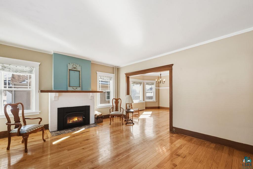 4220 McCulloch Street Duluth, MN 55804 - Photo 2 of 27 Sitting room with light wood-style floors, crown molding, a chandelier, and a fireplace with flush hearth