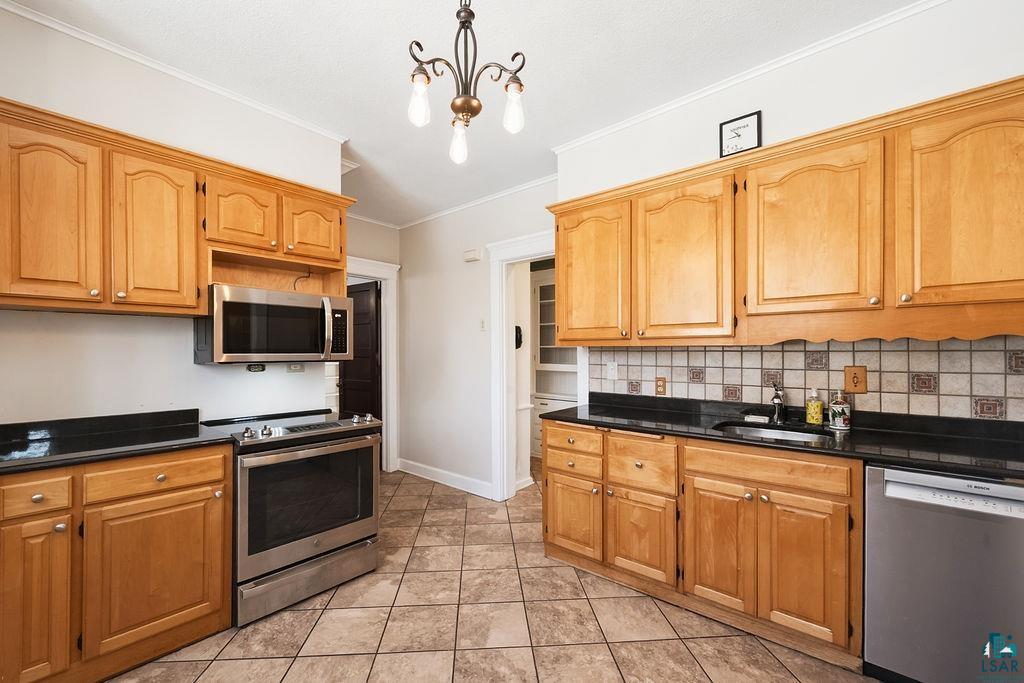 4220 McCulloch Street Duluth, MN 55804 - Photo 7 of 27 Kitchen with ornamental molding, stainless steel appliances, decorative backsplash, hanging lights, and light tile patterned flooring