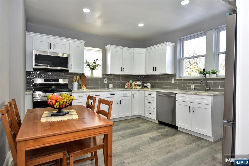 228 Ridgefield Avenue Bogota, NJ 07603 - Photo 11 of 29 a kitchen with stainless steel appliances granite countertop a stove a sink a microwave a refrigerator and white cabinets