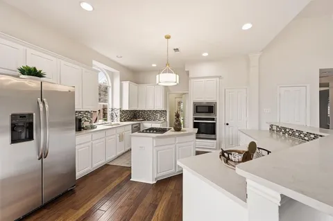 a kitchen with a sink stainless steel appliances and white cabinets