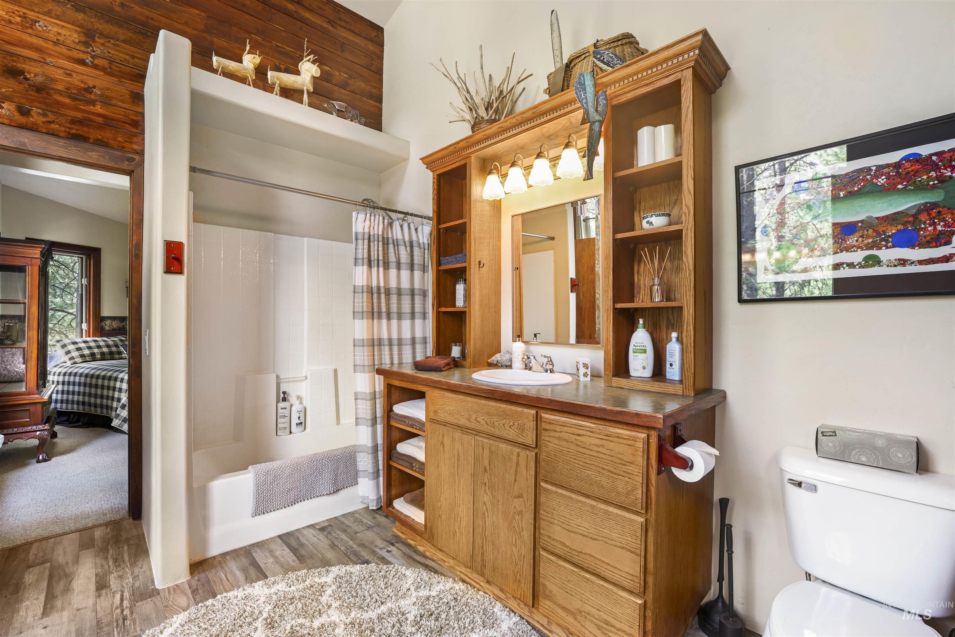 224 Dakota Road Mountain Home, ID 83647 - Photo 20 of 50 Bathroom featuring a tub/shower combination, a wood-finish vanity with an integrated sink, built-in shelving, wood-finish flooring, and a toilet