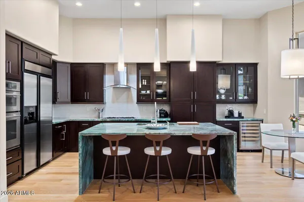 a kitchen with stainless steel appliances granite countertop a stove a refrigerator a sink a dining table and chairs