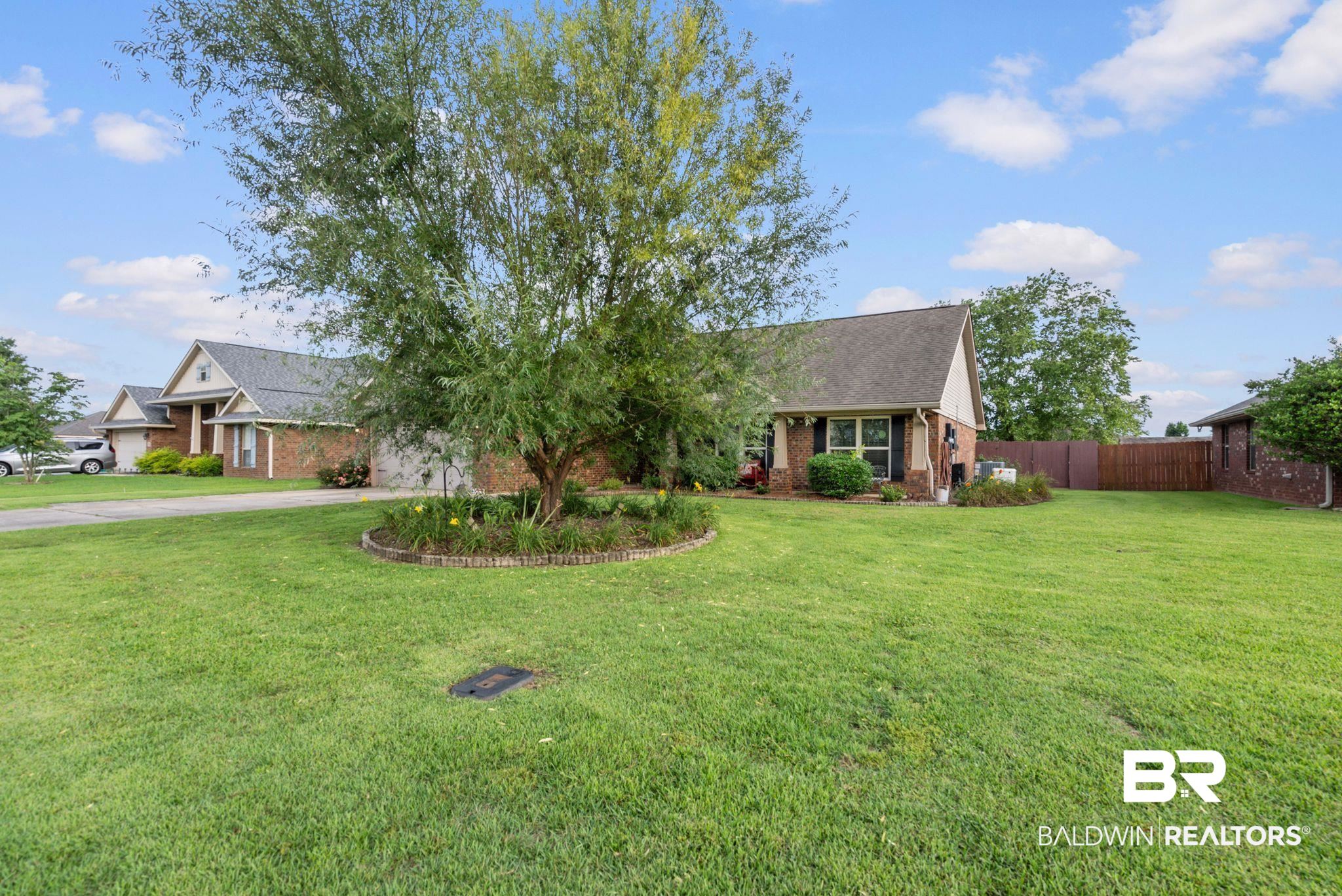 562 Vestige Mews Foley, AL 36535 - Photo 4 of 54 Expansive front yard with a large mature tree centered in a landscaped bed