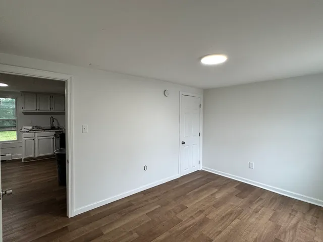 a view of empty room with wooden floor and electronic appliances