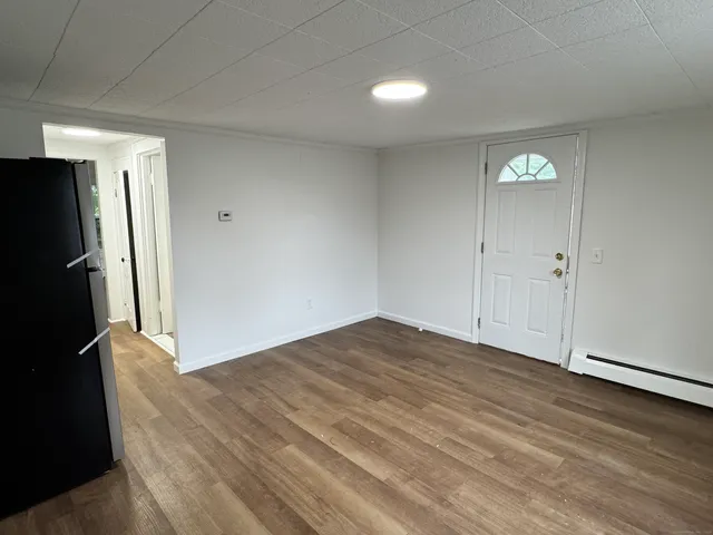 a view of an empty room with window and wooden floor