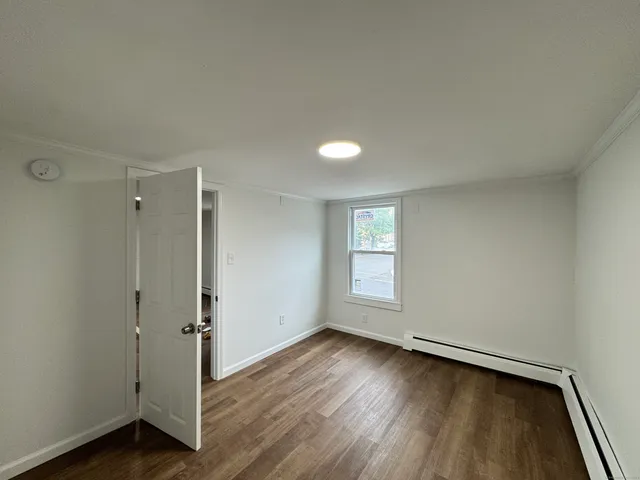 an empty room with wooden floor and window