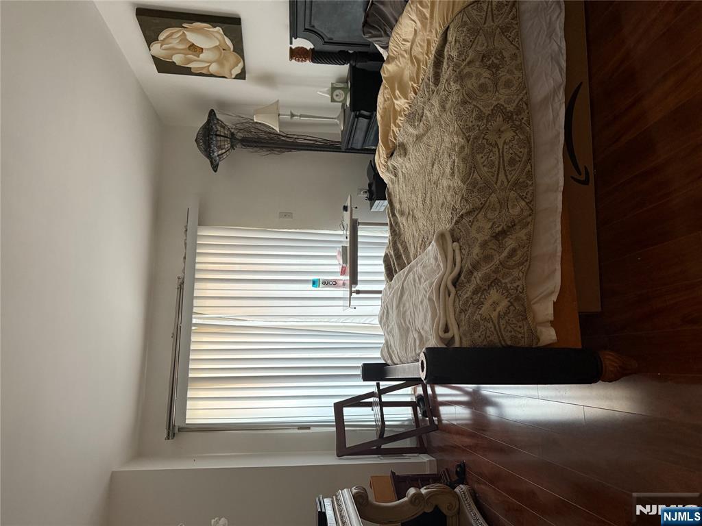 402 Williams Court, Unit U402 Edgewater, NJ 07020 - Photo 6 of 7 a bedroom with a bed and wooden floor