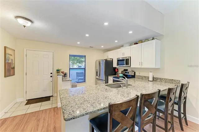 a kitchen with stainless steel appliances granite countertop a table and chairs in it