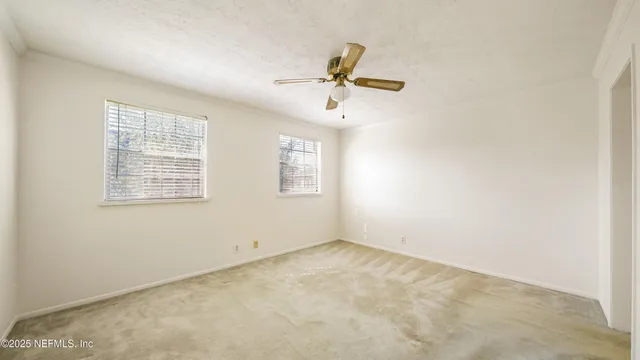 an empty room with windows and fan