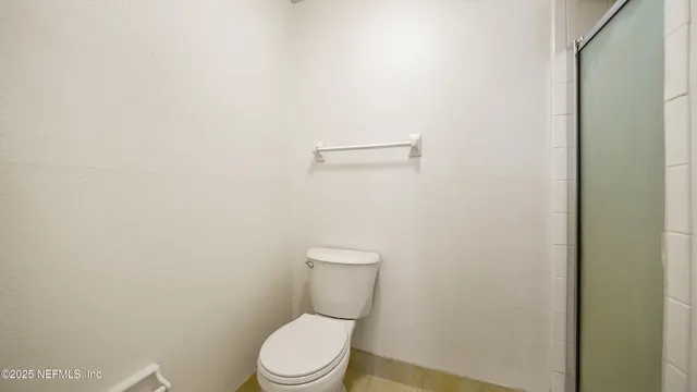 a white toilet sitting next to a white wall
