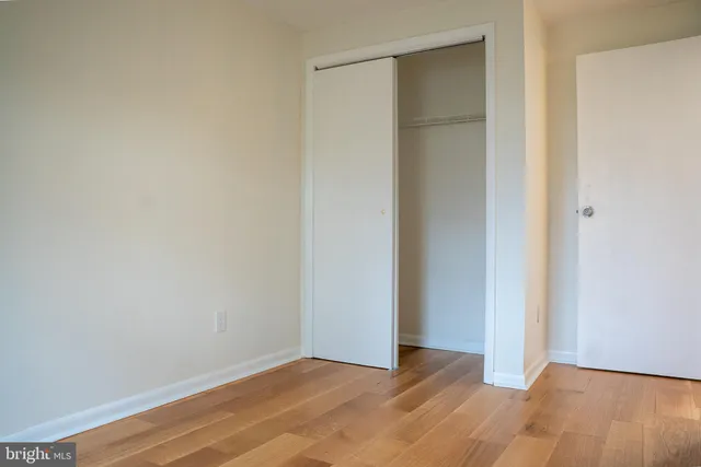 a view of an empty room with wooden floor and closet