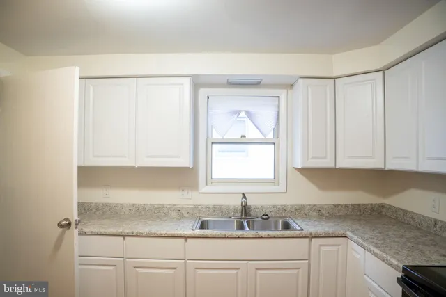 a kitchen with granite countertop white cabinets and a sink
