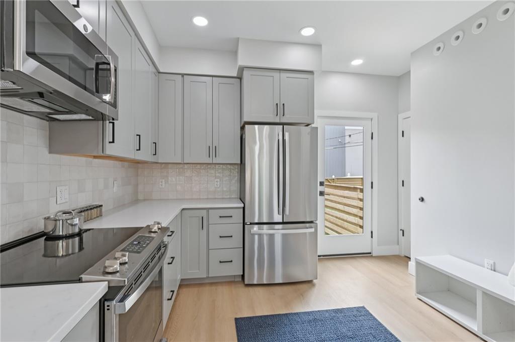 1211 Boyle Street Pittsburgh, PA 15212 - Photo 10 of 38 a kitchen with stainless steel appliances a refrigerator a sink and wooden floors