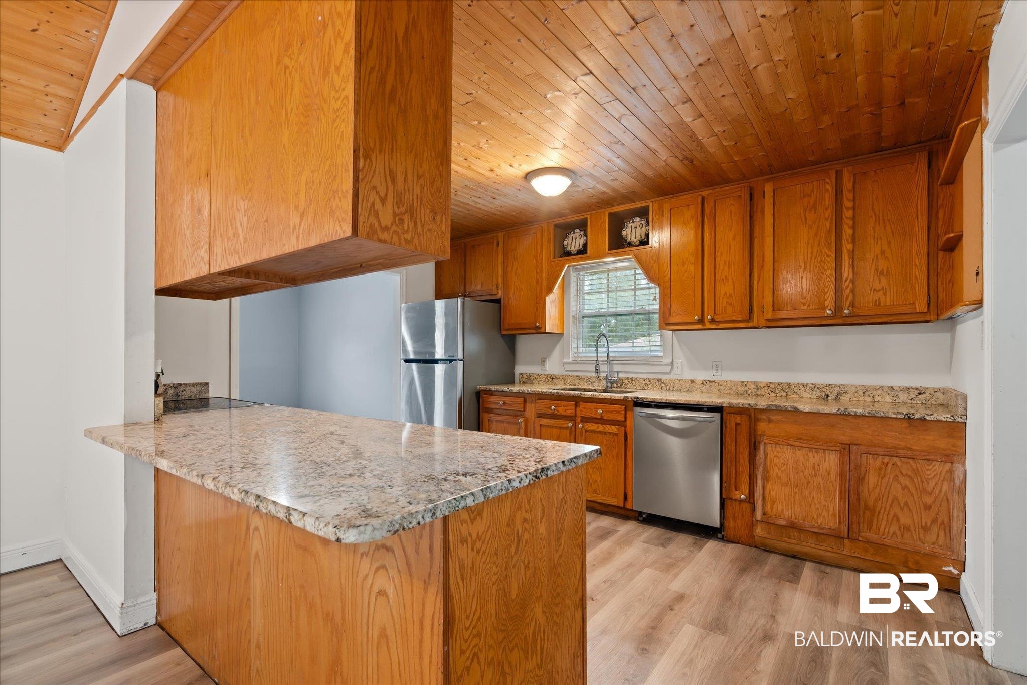 9445 Howells Ferry Road Semmes, AL 36575 - Photo 5 of 20 Kitchen featuring light hardwood / wood-style floors, kitchen peninsula, light stone counters, appliances with stainless steel finishes, and wood ceiling