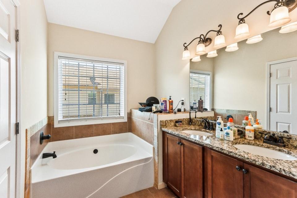 1946 Appaloosa Mill Circle Northeast Buford, GA 30519 - Photo 12 of 20 a bathroom with a granite countertop sink a large mirror a bathtub and window