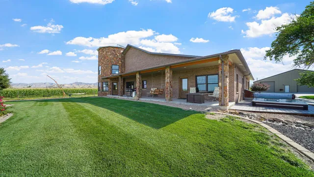 a view of a brick house with a big yard and large trees