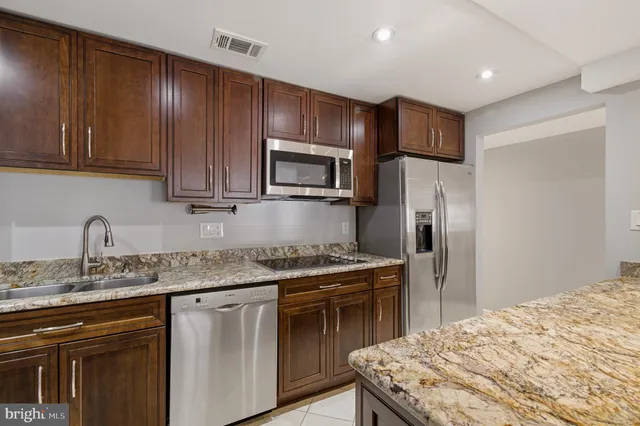 a kitchen with stainless steel appliances kitchen island granite countertop a refrigerator and a sink