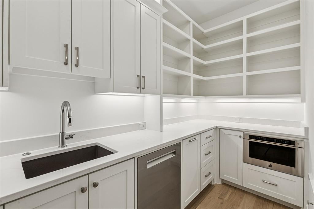 871 Beechwood Lane Fairview, TX 75069 - Photo 11 of 40 a kitchen with a sink dishwasher and white cabinets with wooden floor