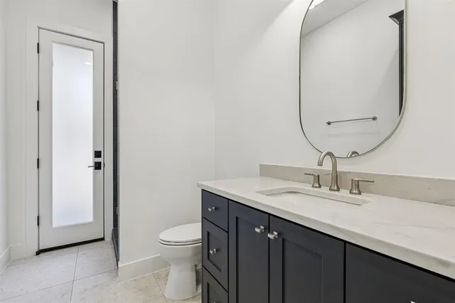 a bathroom with a granite countertop toilet a sink and a mirror