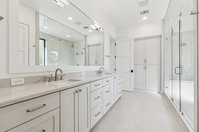 a spacious bathroom with a double vanity sink a large mirror and shower