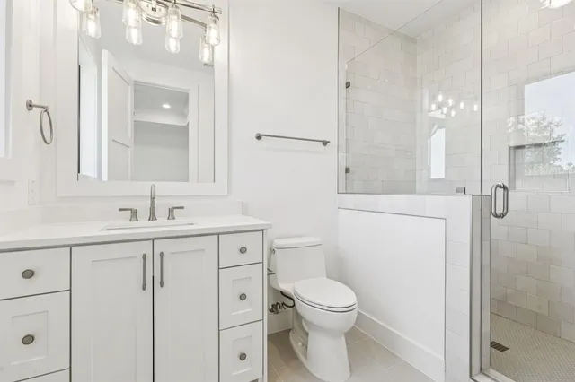 a bathroom with a toilet a sink a mirror and shower
