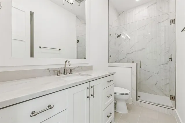 a bathroom with a granite countertop sink a toilet and a shower