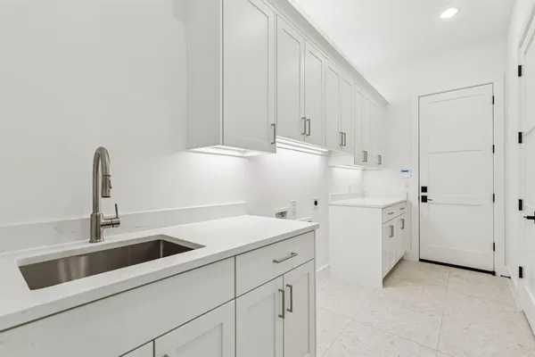 a kitchen with white cabinets and sink