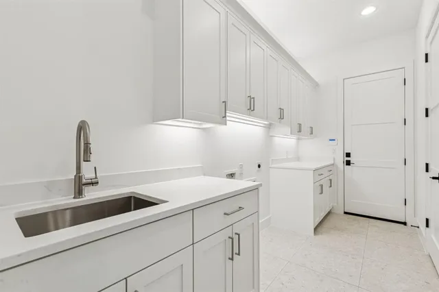 a kitchen with white cabinets and sink