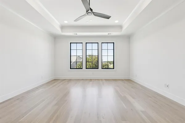 an empty room with wooden floor chandelier and windows