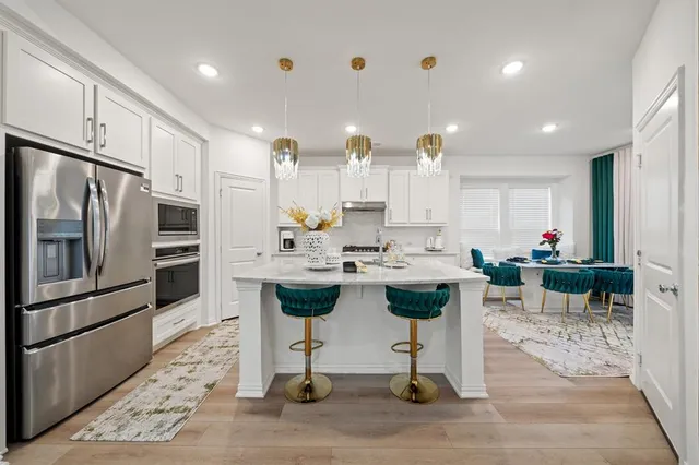 a kitchen with stainless steel appliances kitchen island granite countertop a sink a stove a refrigerator cabinets and chairs