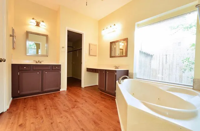 a spacious bathroom with a tub sink and mirror