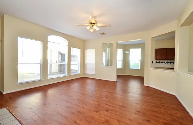 a view of an empty room with window and wooden floor