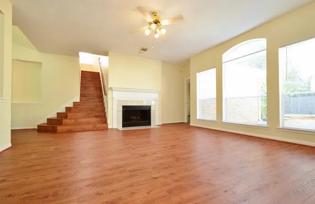 a view of empty room with wooden floor and fan